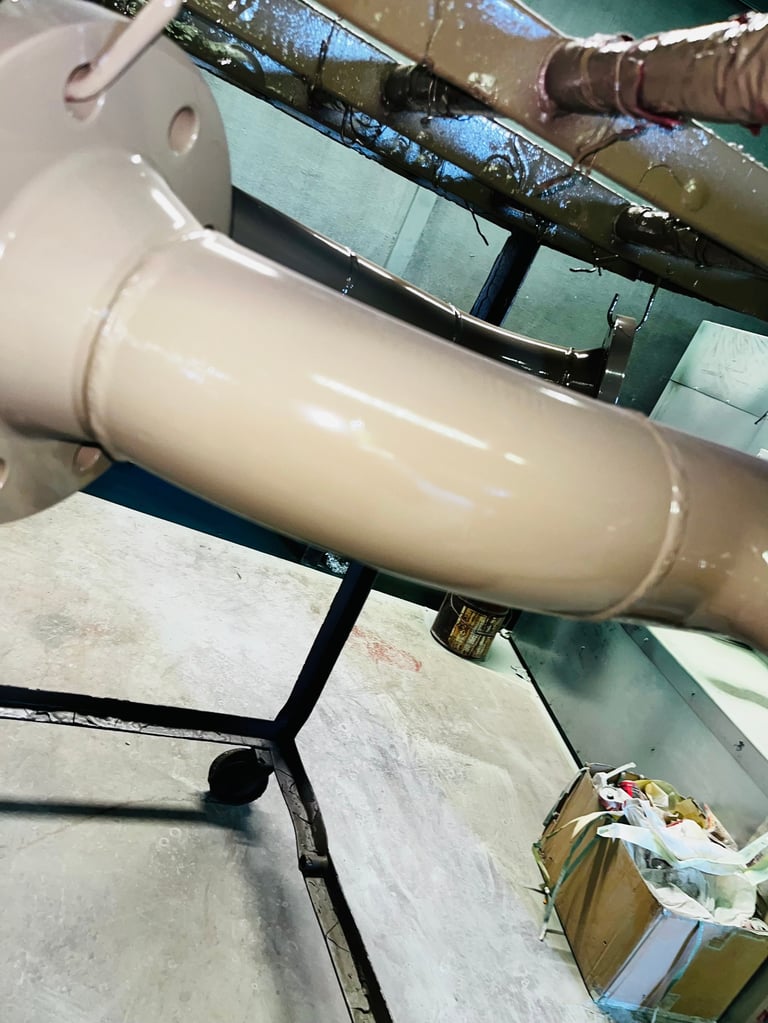 Cream-colored insulated pipe sections connected with black metal bands in an industrial or construction setting